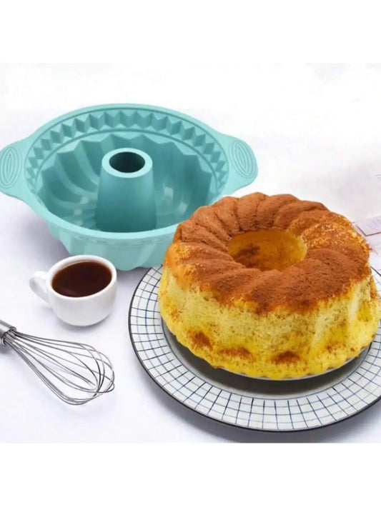 Silicone bundt cake mould with freshly baked cake, coffee cup, and whisk – perfect for baking.